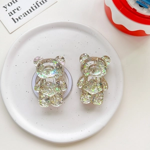 Close-up of two bear-shaped phone grips with aurora glitter sequins in a ceramic dish