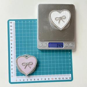 Macro shot of rhinestone bow heart phone stand on scale showing 34.4g weight