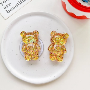 Macro shot of gold holographic glitter bear-shaped resin phone socket on a white plate