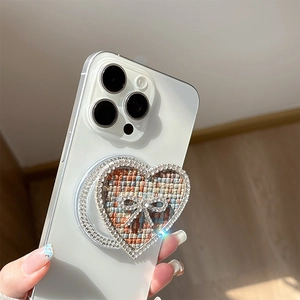 Detail of heart-shaped phone grip with tweed texture and rhinestone bow decoration