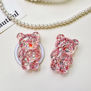 Close-up of cute pink glitter bear phone socket stands on a textured surface