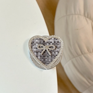 Detail showing tweed fabric texture and sparkling rhinestone bow on heart phone socket