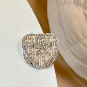Macro shot of heart-shaped phone grip with tweed fabric and rhinestone bow detail