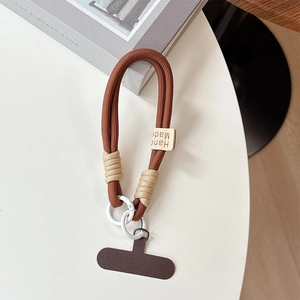 Macro view of thick brown braided phone wrist strap with coffee T-patch and clip
