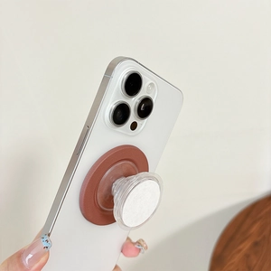 Minimalist magnetic phone grip with brown leather texture and clear airbag on white phone