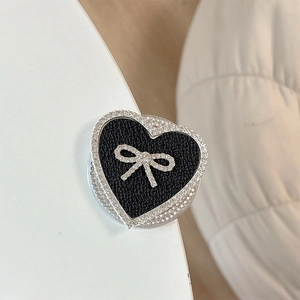 Macro detail of heart-shaped phone grip with leather texture and rhinestone bow decoration