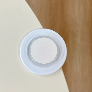 Close-up of a white circular magnetic phone socket stand on a minimalist desk corner