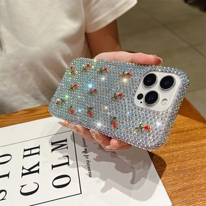 Close-up of a luxury iPhone case with red roses and sparkling rhinestones in a hand