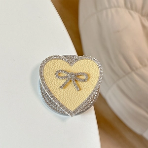Macro shot of heart phone grip with yellow leather texture and rhinestone bow detail