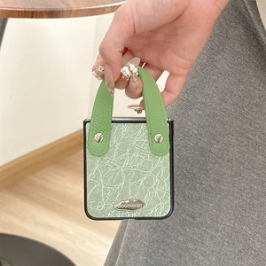 Detail of light green textured leather phone bag with handle and silver metal buckle