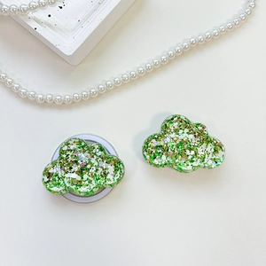 Detail of cloud-shaped phone grip with green and gold sequins in clear resin