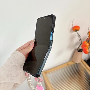 Détail de la coque pliable bleue avec bracelet de perles et breloque cœur rose