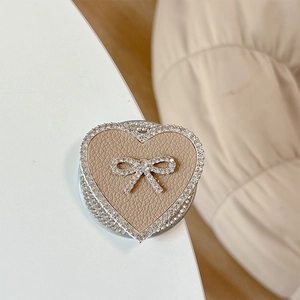 Macro side view of khaki leather heart phone socket with rhinestone bow and trim