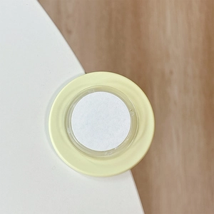 Close-up of a round yellow silicone corner protector with adhesive back on a white desk