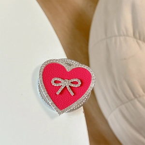 Detail of a heart-shaped phone grip with rose red leather texture and crystal bow