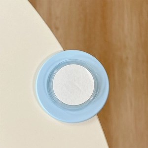 Detail of a light blue round adhesive corner protector installed on white furniture