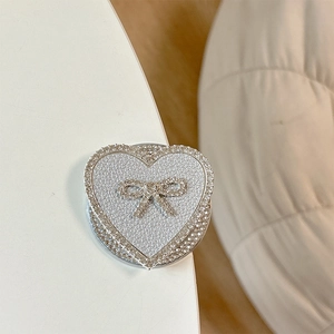 Macro shot of silver leather heart phone stand with rhinestone bow and luxury finish