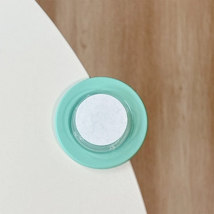 Detailed top view of mint green silicone corner protector with adhesive pad on wood surface