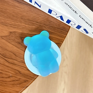 Supporto per telefono a orso blu traslucido su un tavolo in legno scuro di design