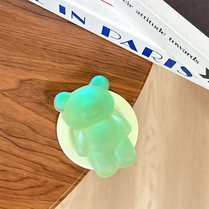 Macro del supporto per cellulare a forma di orso verde trasparente su tavolo in legno