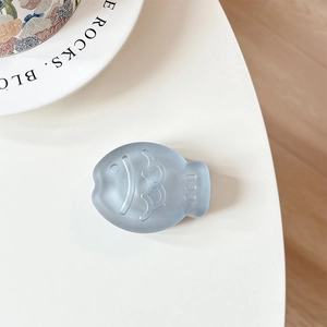 Macro shot of matte blue fish-shaped phone grip on a white minimalist background