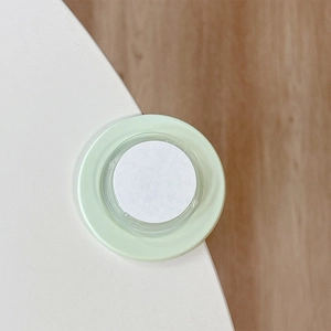 Macro detail of a soft mint green silicone corner protector on a white desk edge