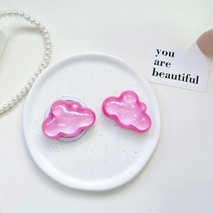 Close-up of pink glitter cloud phone socket stand on a ceramic tray with pearls