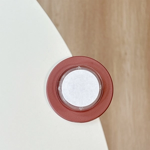 Close-up of a reddish-brown round corner protector mounted on a white furniture edge