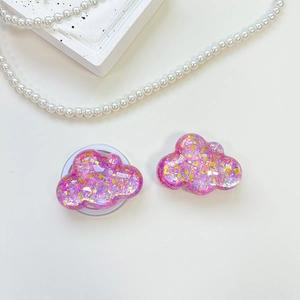 Close-up of cloud-shaped phone grips with pink purple sequins and iridescent resin finish