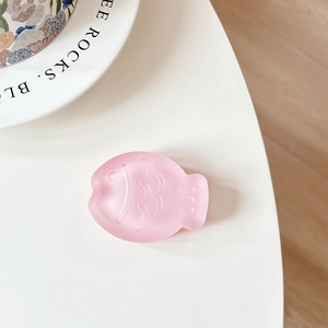 Close-up of pink translucent matte fish-shaped phone grip with a smooth frosted finish