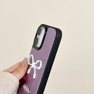 Detail view of purple leather phone case with white polka dot bow and metal tag