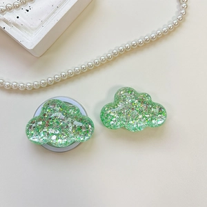 Detail view of cloud-shaped phone grip with sparkling green sequins and resin finish