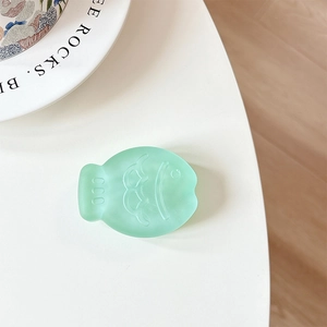 Macro detail of mint green fish-shaped phone grip with matte textured scale design