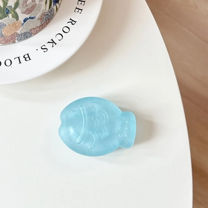 Macro detail of a light blue matte taiyaki fish-shaped phone grip with scales texture