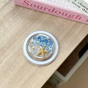 Detail view of ocean-themed phone grip with starfish, seashells, and blue stones décor