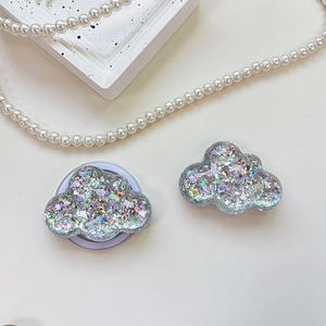 Detail of cloud-shaped phone grip with glitter sequins on a decorative background