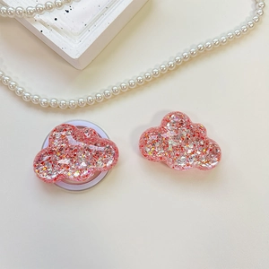 Detailed view of cloud-shaped phone grip with pink glitter and sequins on a white surface