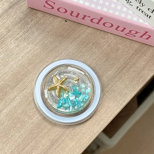 Detailed close-up of a round resin ocean-themed phone grip with starfish and blue stones
