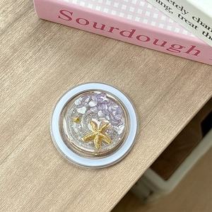 Detail of magnetic phone grip featuring sea shells, purple stones and golden starfish