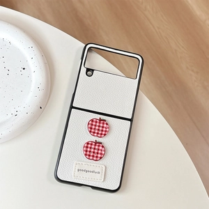 Detail of leather foldable phone case featuring checkered apple buttons and stitched label