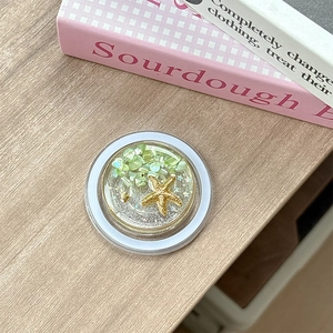 Detailed close-up of a resin phone grip featuring a starfish and colorful sea stones