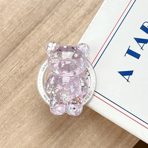 Detail of bear phone grip with sparkling laser sequins and purple resin on a wooden desk