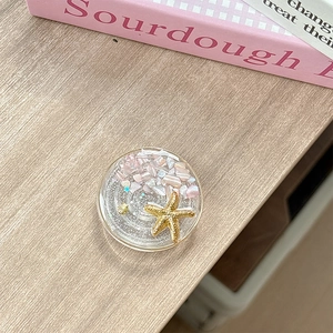 Detail shot of ocean theme resin phone grip with pink stones and a golden starfish