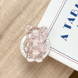 Detail view of pink glitter bear phone grip with sparkling sequins on wooden surface