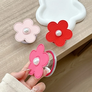Floral pearl leather phone grip stand in pink and red tones on a wooden desk
