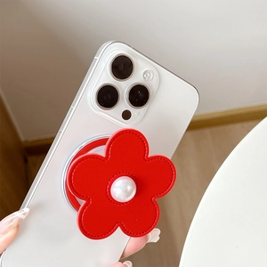 Macro detail of red faux leather flower phone grip with central pearl on clear case