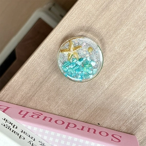Macro view of ocean-style phone grip featuring sea stars and shells on a wooden background