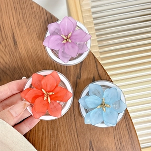 Trois supports de téléphone en forme de fleur translucide en violet, orange et bleu