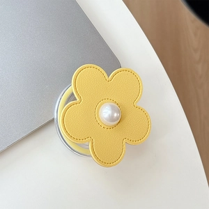 Detail of yellow lychee leather flower phone stand with central pearl on a laptop