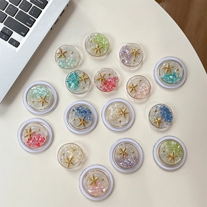 Magnetic ocean-themed phone grips with starfish and colorful stones on a white desk